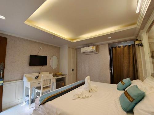 Habitación de hotel con cama, escritorio y TV. en Mo rooms en Chiang Mai
