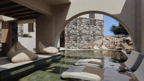 une maison avec une piscine avec des chaises et un mur de pierre dans l'établissement Elounda Stories Boutique Hotel, à Elounda