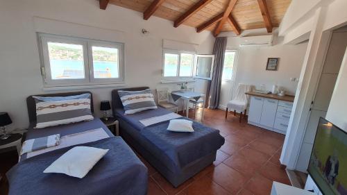 a room with two beds and a kitchen with windows at Apartments Valentina Tisno in Tisno