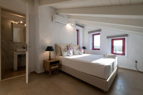 a white bedroom with a large bed and a sink at Abeloessa Methonian Hospitality in Methoni