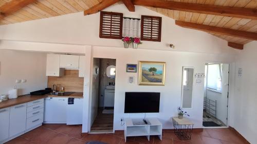 a kitchen with white cabinets and a flat screen tv at Apartments Valentina Tisno in Tisno