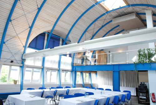 a large room with white tables and blue chairs at Hotel Georg in Witten