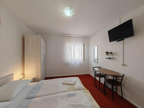 a bedroom with a bed and a table and a television at Apartments & Rooms Samohod in Vodice