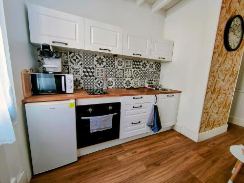 une cuisine avec des armoires blanches et un micro-ondes dans l'établissement Rêves & Bois - Séjour à Auxerre, à Auxerre