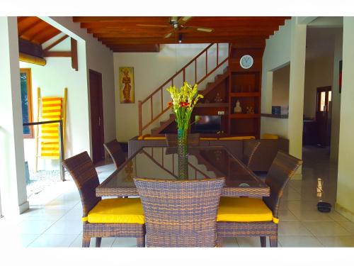 a dining room table with chairs and a vase with yellow flowers at Juada Garden in Seminyak