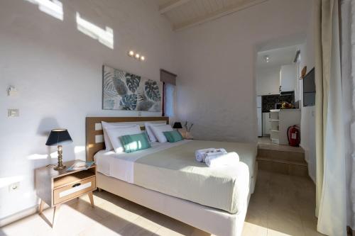 a bedroom with a large white bed and a kitchen at Abeloessa Methonian Hospitality in Methoni