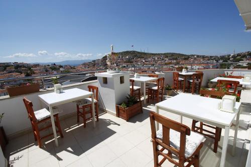 a balcony with tables and chairs and a view of a city at Bonapart Hotel in Çeşme