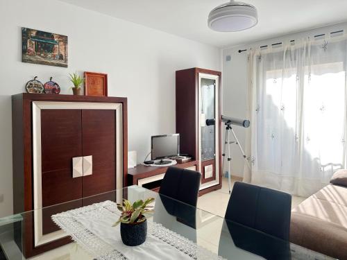 ein Wohnzimmer mit einem Glastisch und einem TV in der Unterkunft Sueños de Monachil in Monachil