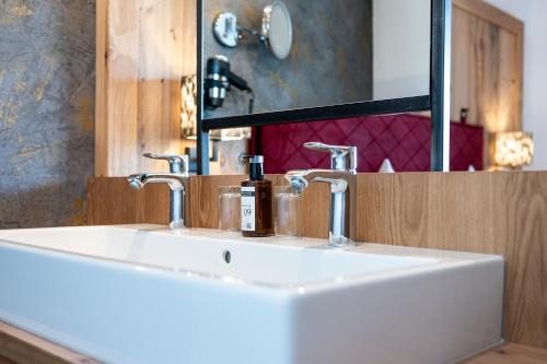 a white sink in a bathroom with a mirror at Hotel Almschlössl & Schrotteralm in Obertauern