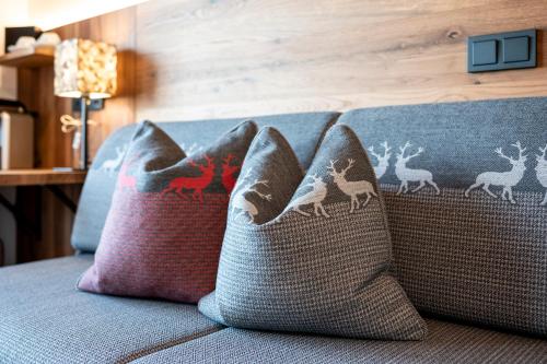 a couch with three pillows on it with at Hotel Almschlössl & Schrotteralm in Obertauern