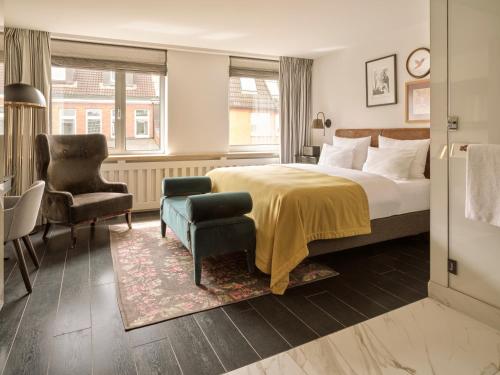 a hotel room with a bed and a chair at The Nikolai Hamburg - Leonardo Limited Edition in Hamburg