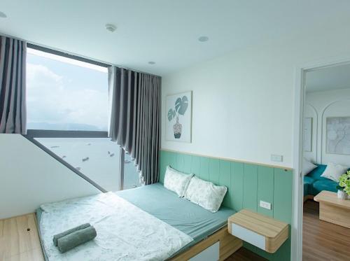 un letto in una camera con una grande finestra di Green Diamond Homestay Hạ Long a Ha Long