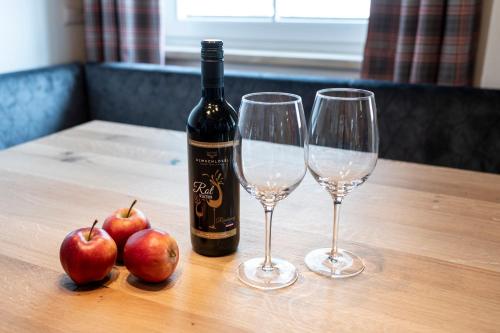 two glasses of wine and two apples on a table at Hotel Almschlössl & Schrotteralm in Obertauern