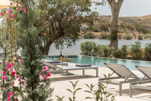 a pool with chairs and a table with a bottle of wine at oKEAnõs in Vourkarion