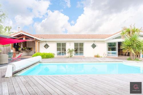 une maison avec une piscine et une maison dans l'établissement Villa avec piscine pour 8 personnes à Biscarrosse bourg, à Biscarrosse