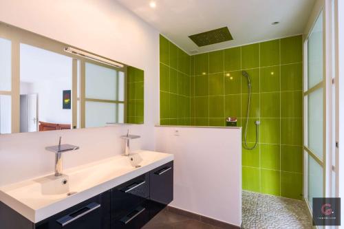 La salle de bains est pourvue d'un lavabo et d'une douche avec du carrelage vert. dans l'établissement Villa avec piscine pour 8 personnes à Biscarrosse bourg, à Biscarrosse