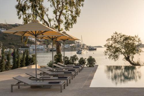 a row of lounge chairs and an umbrella next to a body of water at oKEAnõs in Vourkarion