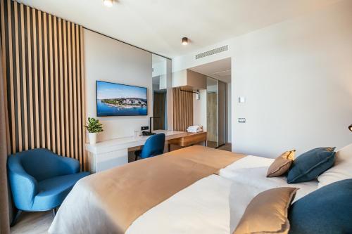 una camera con un grande letto e sedie blu di Hotel Riviera - Terme & Wellness Lifeclass a Portoroz