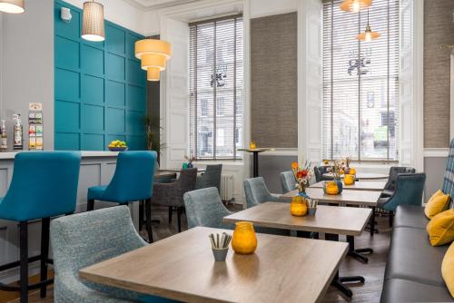 un restaurante con paredes azules, mesas y sillas en 28 York Place Hotel en Edimburgo