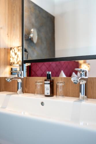a bathroom sink with two faucets and a mirror at Hotel Almschlössl & Schrotteralm in Obertauern
