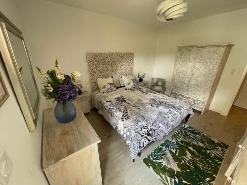 - une chambre avec un lit et un vase de fleurs dans l'établissement L'hortensia bleu, à Saint-Malo