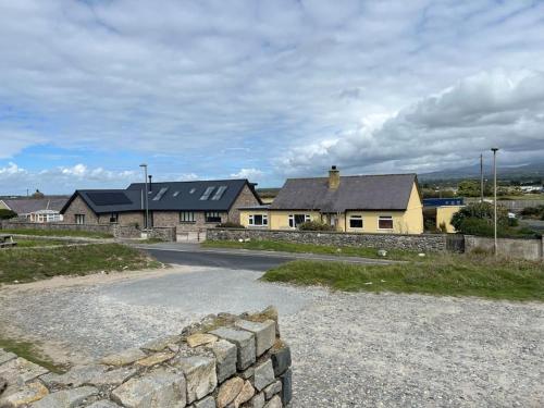 a house with a stone wall next to a road at Seafront cottage Dinas Dinlle in Caernarfon