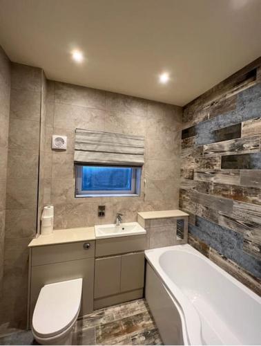 a bathroom with a tub and a toilet and a sink at Seafront cottage Dinas Dinlle in Caernarfon