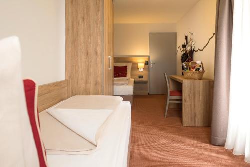 a hotel room with a bed and a desk at Dorint Blüemlisalp Beatenberg/Interlaken in Beatenberg