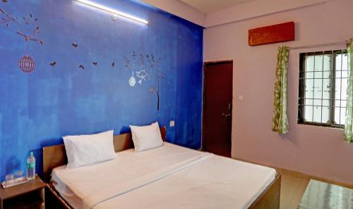 een slaapkamer met een bed met een blauwe muur bij Hotel Sambodhi Palace in Bhopal