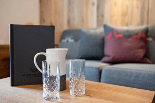 two glasses on a table next to a couch at Hotel Almschlössl & Schrotteralm in Obertauern