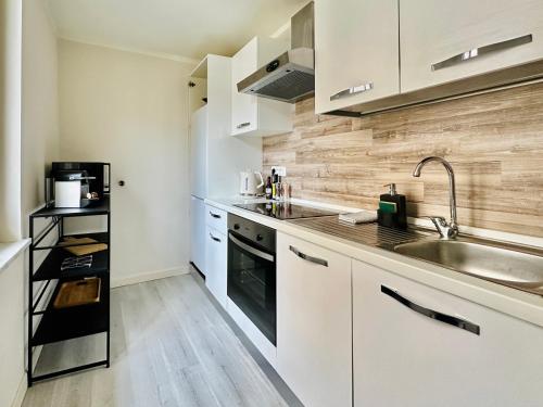 une cuisine avec des armoires blanches et un évier dans l'établissement Le duplex - 2 pièces centre Cannes, à Cannes