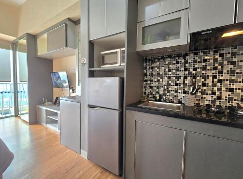 a kitchen with a refrigerator and a microwave at Apt Casa De Parco Studio Tema Gray With Wifi, Pool and Netflix in Samporo
