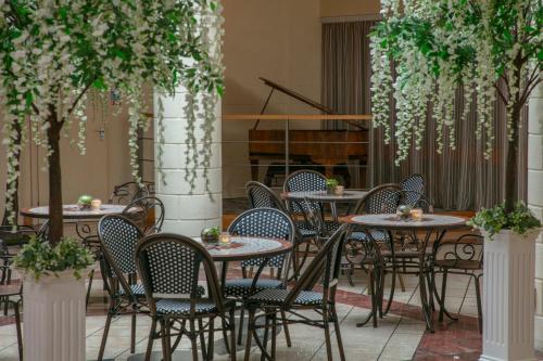 a group of tables and chairs in a courtyard with trees at The Suites Hotel & Spa Knowsley - Liverpool by Compass Hospitality in Knowsley
