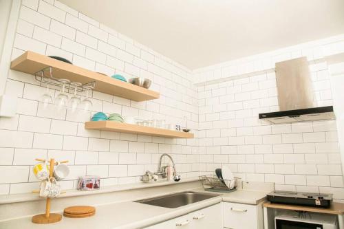 a white tiled kitchen with a sink and a counter at R House in Seoul