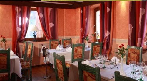 une salle à manger avec des tables, des chaises et des rideaux rouges dans l'établissement Hotel Restaurant A l'Ange, à Climbach