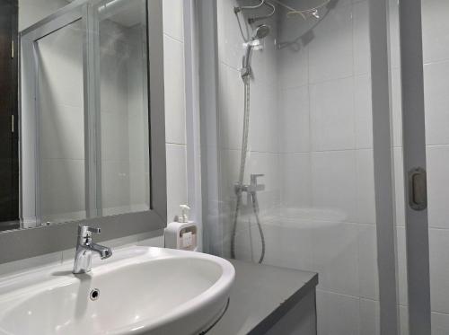 a white bathroom with a sink and a shower at Apt Casa De Parco Studio Tema Gray With Wifi, Pool and Netflix in Samporo