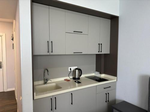 una cucina con mobili bianchi e un lavello di Alliance Palace By Marriott a Batumi