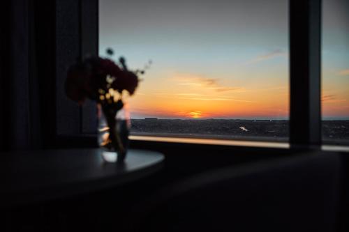 a vase of flowers in a window with a sunset at Hotel Nikko Kanazawa in Kanazawa