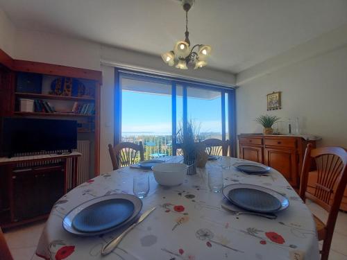 une salle à manger avec une table avec des assiettes et une vue dans l'établissement Royan Pontaillac – APPARTEMENT VUE MER – balcon – WIFI – confort simple, à Royan