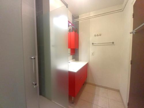 La salle de bains est pourvue d'une armoire rouge et d'un lavabo. dans l'établissement Royan Pontaillac – APPARTEMENT VUE MER – balcon – WIFI – confort simple, à Royan