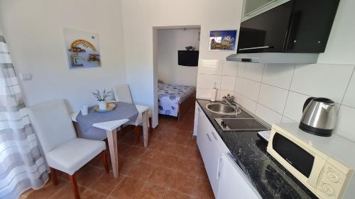 a small kitchen with a sink and a table at Apartments Valentina Tisno in Tisno