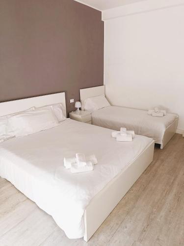 a bedroom with two beds with white sheets at Hotel Bacco Rooms and Breakfast in Pietra Ligure