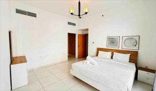- une chambre blanche avec un grand lit blanc et un lustre dans l'établissement Lulu guest house, à Ras al Khaimah