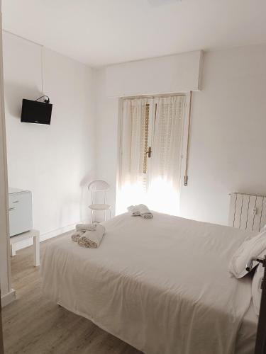 a white bedroom with a bed and a window at Hotel Bacco Rooms and Breakfast in Pietra Ligure