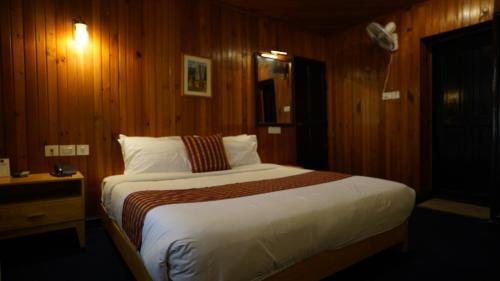 ein Schlafzimmer mit einem großen Bett mit Holzwänden in der Unterkunft Hotel Olathang in Paro