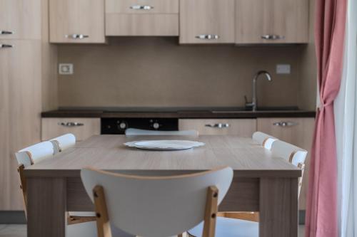 a kitchen with a wooden table and white chairs at Le Dune Verdi in Lido di Jesolo
