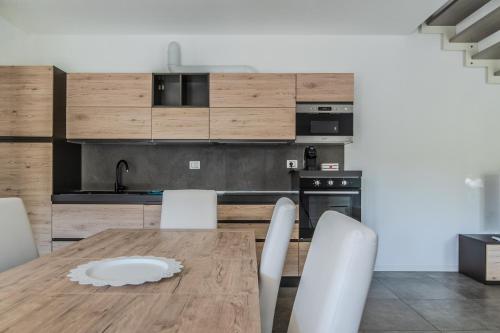 a kitchen with a wooden table and white chairs at Le Dune Verdi in Lido di Jesolo