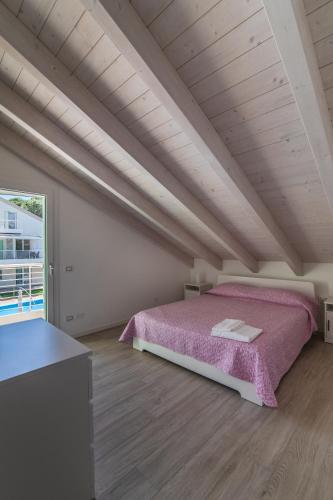 a bedroom with a pink bed in a attic at Le Dune Verdi in Lido di Jesolo