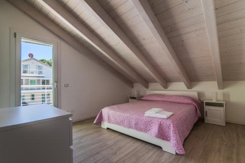 a bedroom with a pink bed and a large window at Le Dune Verdi in Lido di Jesolo