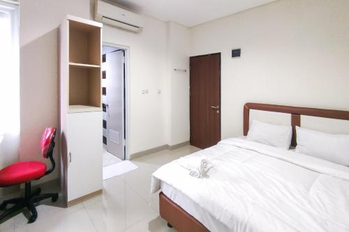 a bedroom with a bed and a red chair at RedDoorz Plus Near ICE BSD Minerva in Cilandak